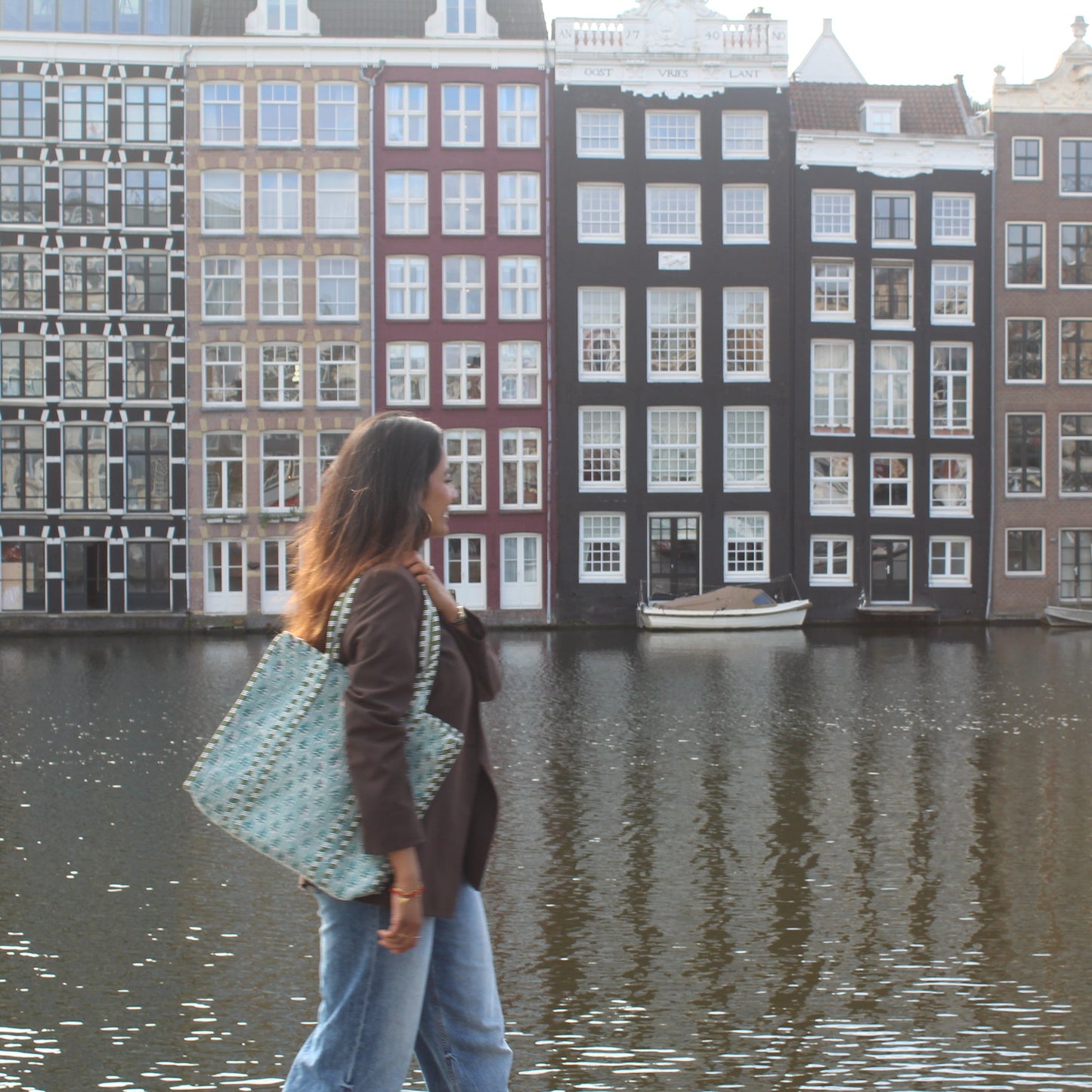 Woman walking by a canal with traditional Dutch houses in the background
