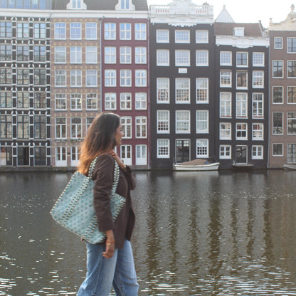 Woman walking by a canal with traditional Dutch houses in the background
