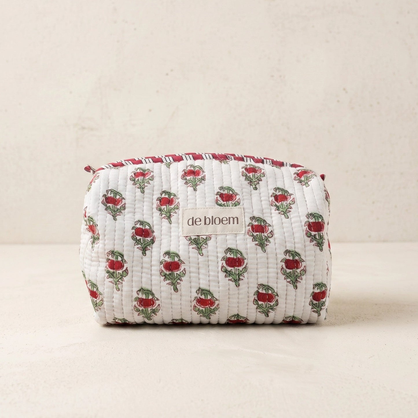 Fabric pouch with floral pattern and 'de bloem' branding on a beige background