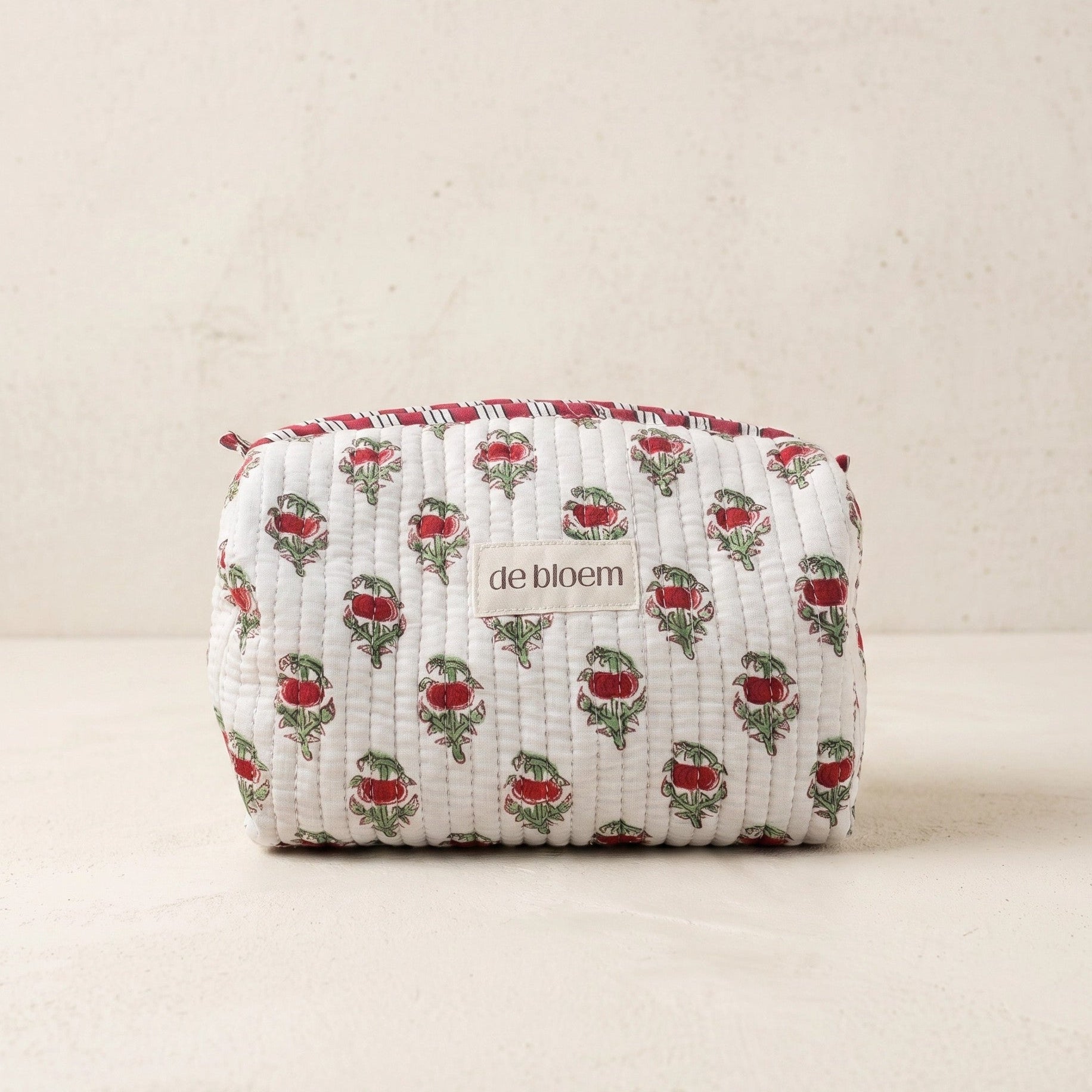Fabric pouch with floral pattern and 'de bloem' branding on a beige background