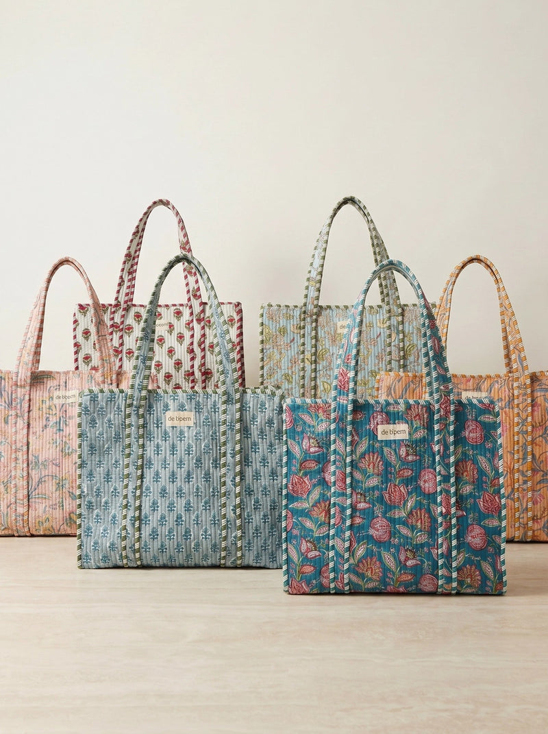Set of colorful cotton handbags on a light wooden surface with a neutral background