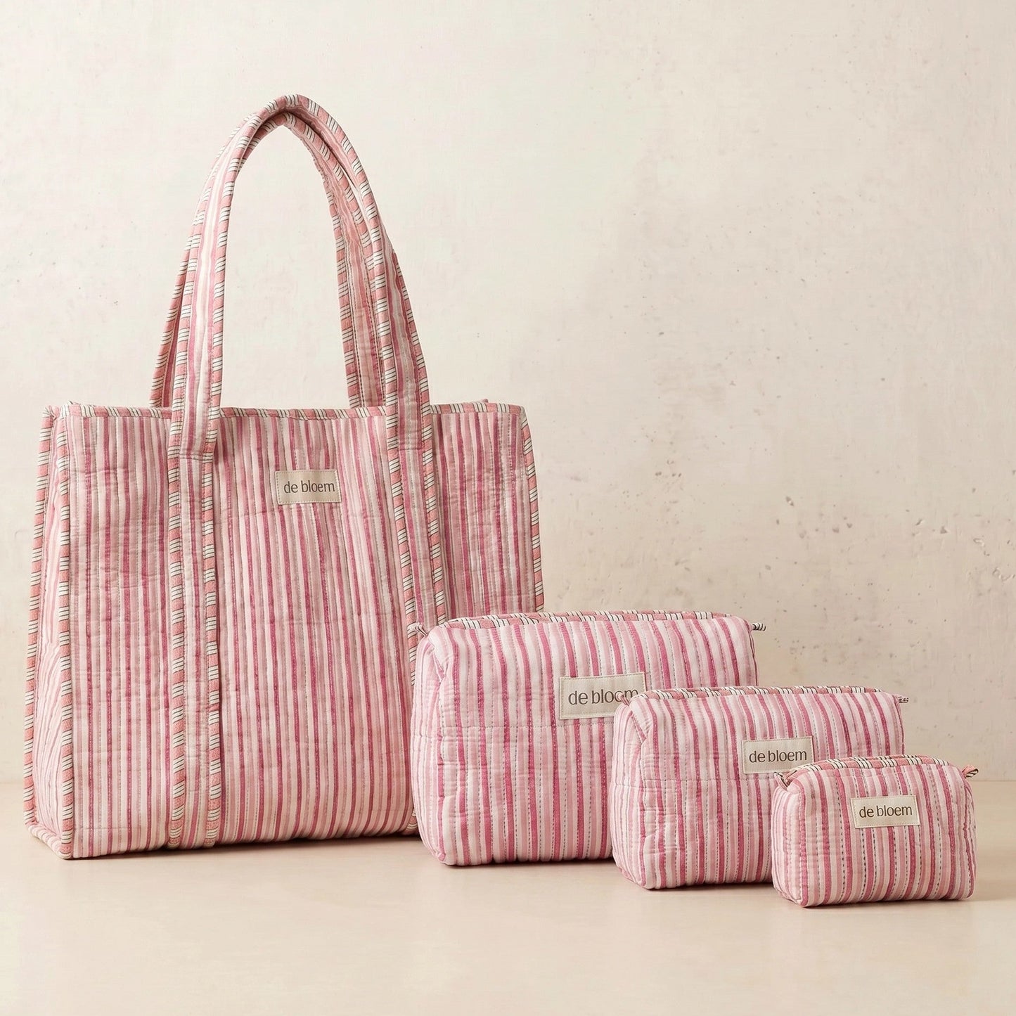 Set of pink striped bags with 'de laine' branding on a light background
