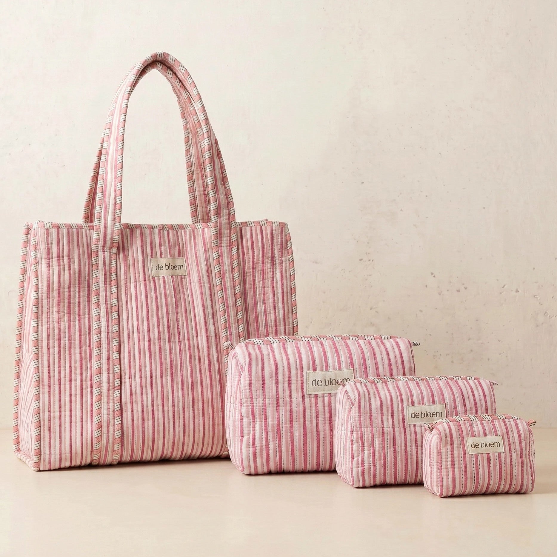 Set of pink striped bags with 'de laine' branding on a light background