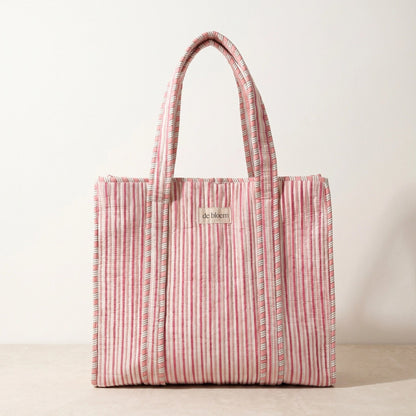 Handmade pink striped quilted cosmetic pouch with a yellow and blue floral print and de bloem logo label.