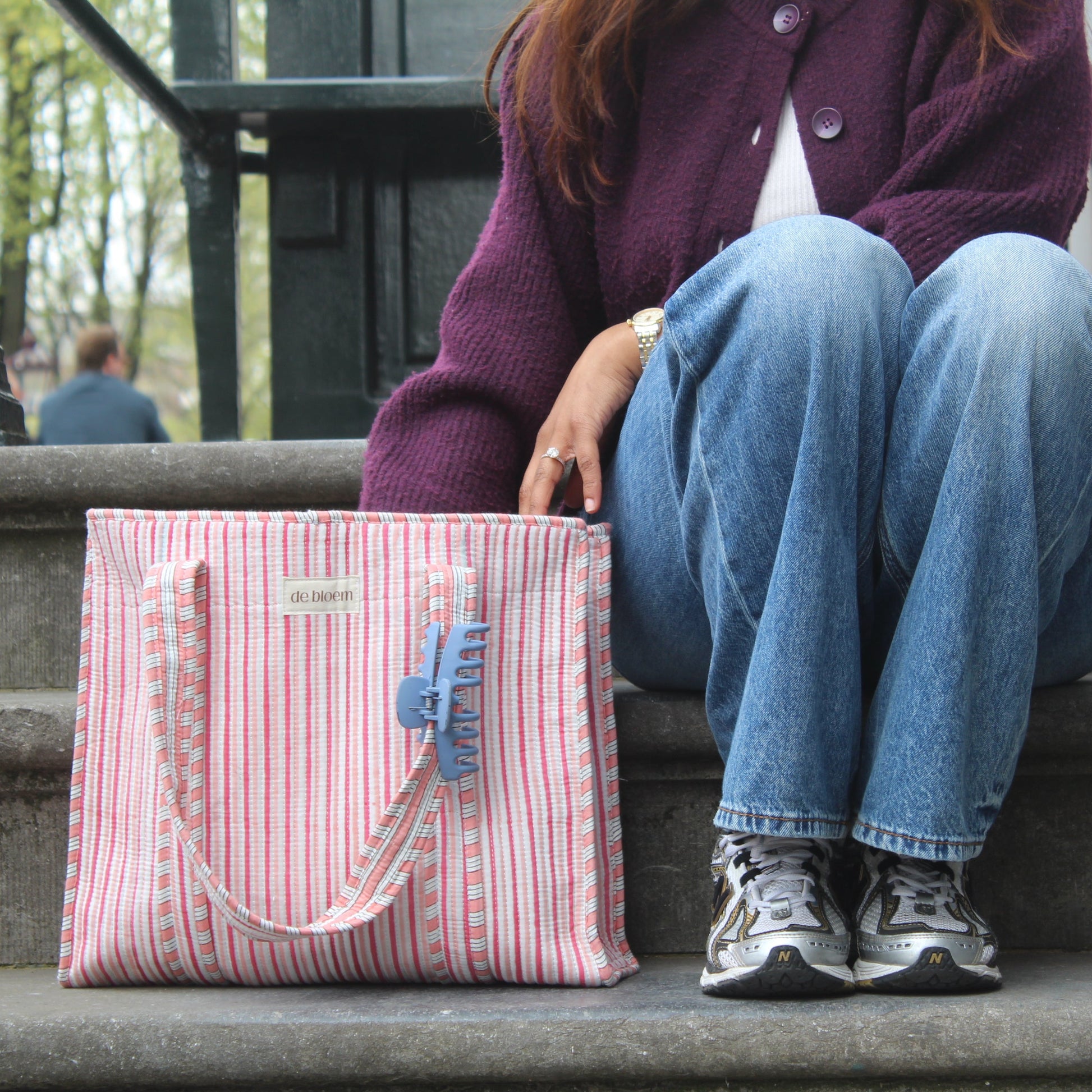 Person sitting on steps with a pink striped bag