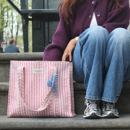 Person sitting on steps with a pink striped bag