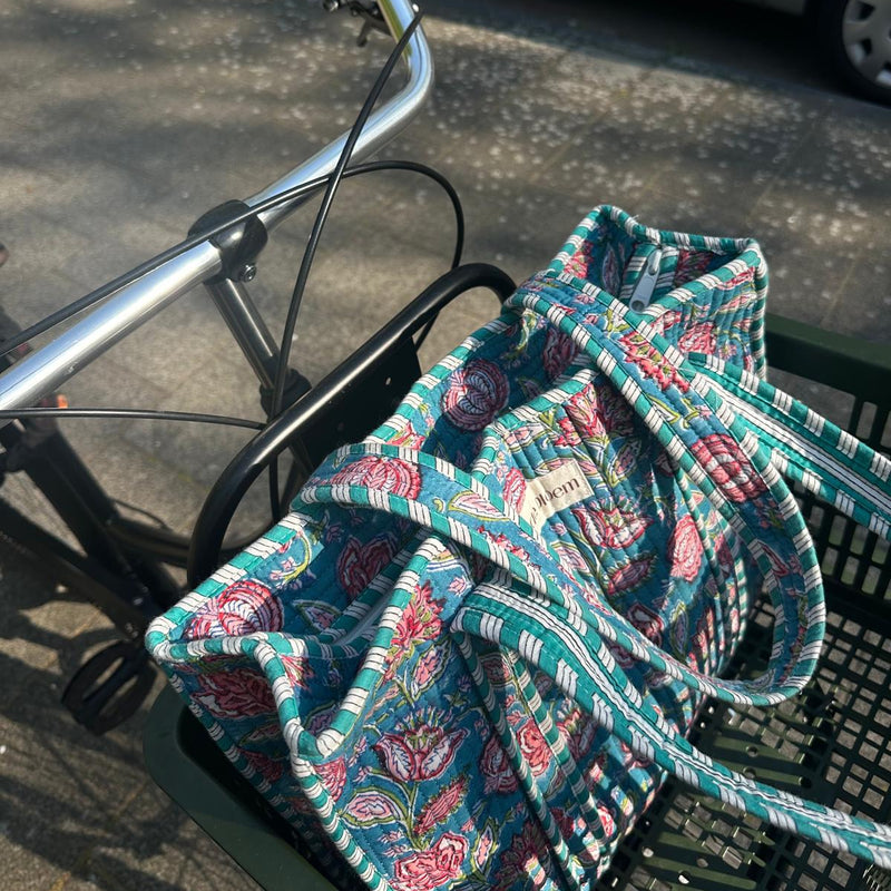 Floral-patterned bag on a bicycle basket with a car in the background