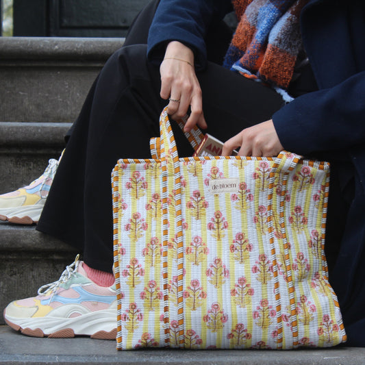 Person sitting on steps holding a floral-patterned bag