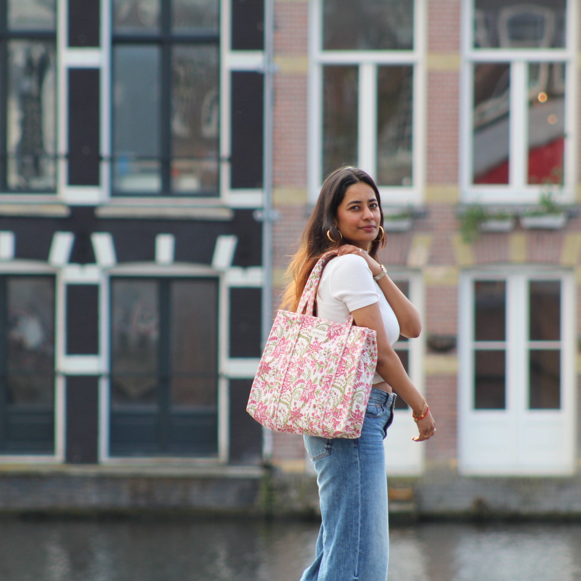 woman holdng pink floral bag in front of Dutch houses