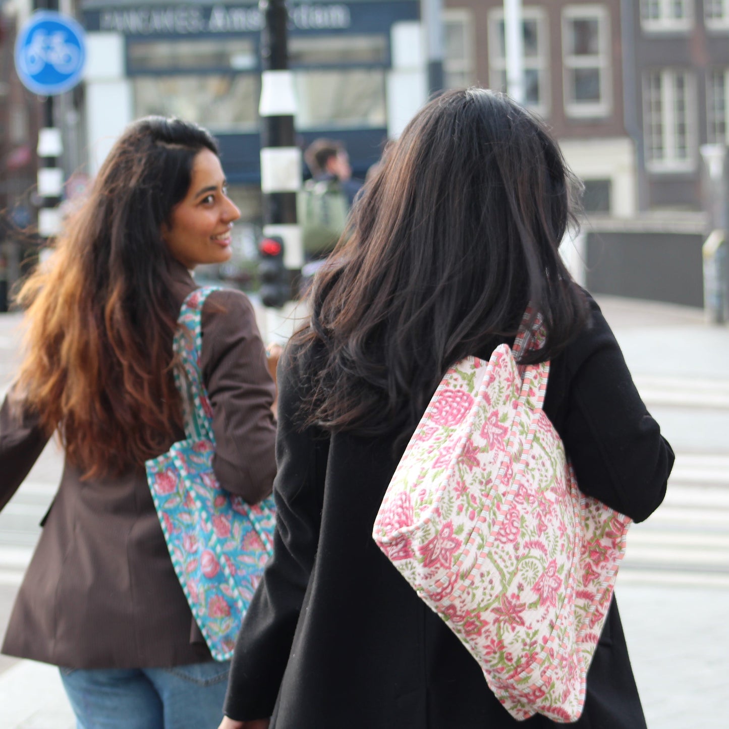 Two women walking outdoors with floral-patterned bags.