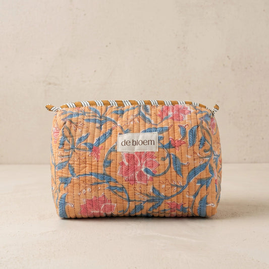 Handmade orange quilted cosmetic pouch with a pink and blue floral print and de bloem logo label.